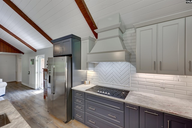 kitchen featuring stainless steel refrigerator with ice dispenser, light wood-type flooring, black electric cooktop, wood ceiling, and lofted ceiling with beams