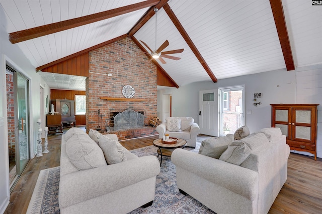living room with ceiling fan, a healthy amount of sunlight, wood finished floors, and a fireplace