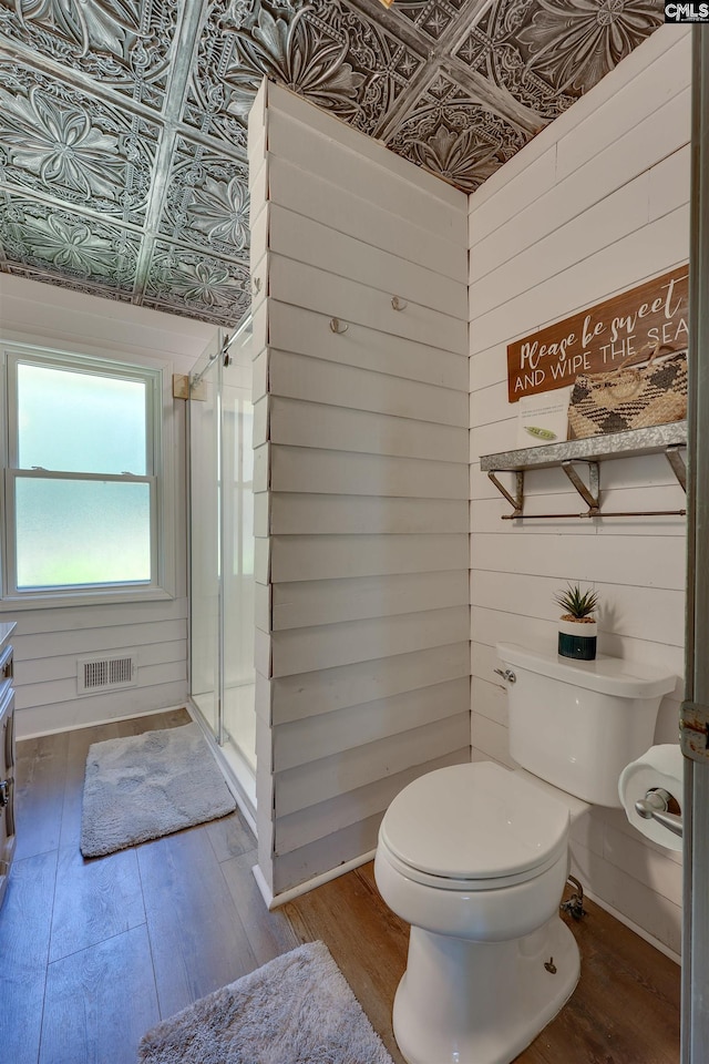 full bath featuring an ornate ceiling, toilet, a shower stall, wood finished floors, and visible vents