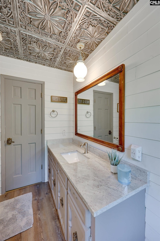 bathroom featuring wooden walls, vanity, an ornate ceiling, and hardwood / wood-style flooring