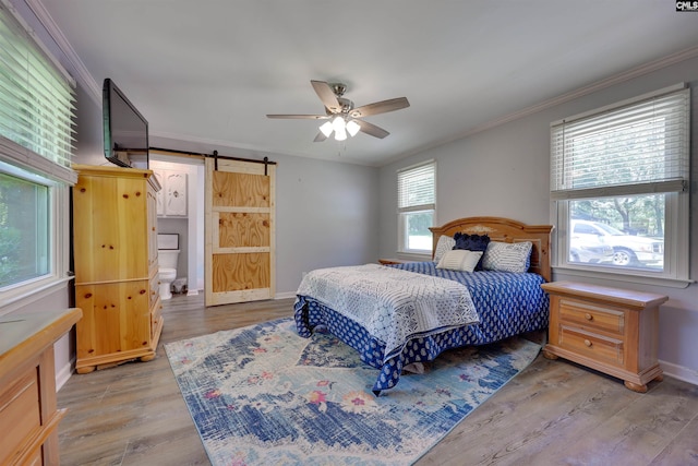 bedroom featuring crown molding, a barn door, a ceiling fan, baseboards, and wood finished floors
