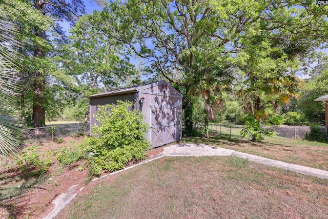 view of yard featuring an outdoor structure, a fenced backyard, and a storage shed