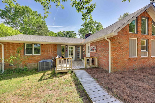 back of house featuring a lawn, a wooden deck, cooling unit, and brick siding