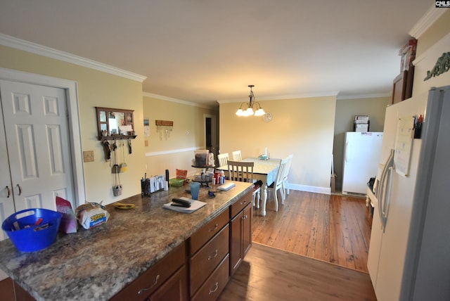 kitchen with crown molding, white refrigerator with ice dispenser, freestanding refrigerator, dark wood-style floors, and a notable chandelier