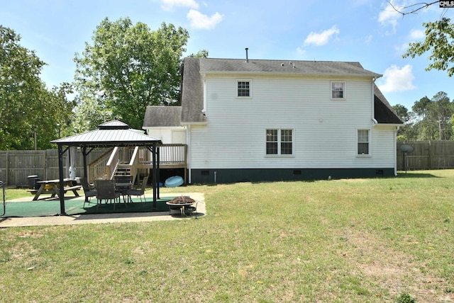 back of house with a gazebo, an outdoor fire pit, crawl space, a fenced backyard, and a lawn