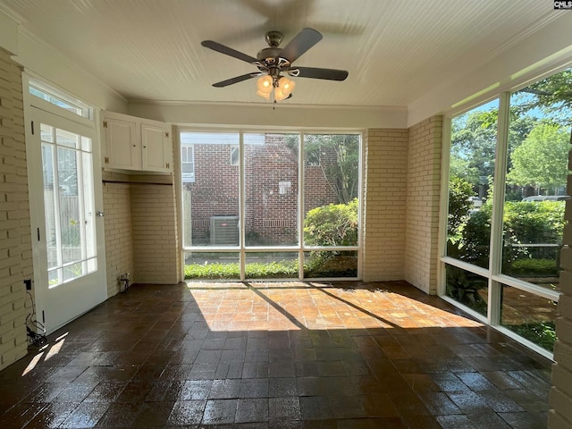 unfurnished sunroom with ornamental molding and brick wall