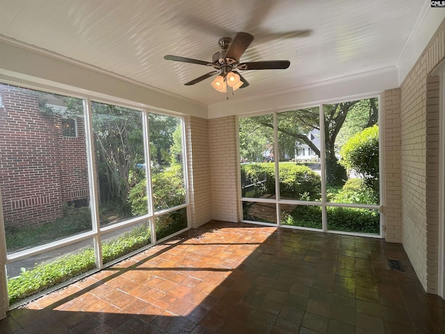 unfurnished sunroom with crown molding, a ceiling fan, and brick wall