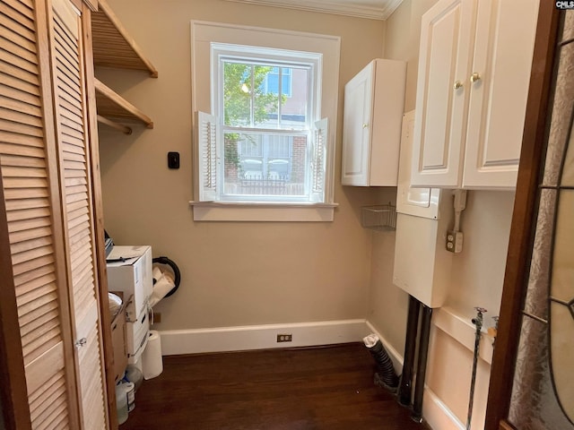 clothes washing area featuring crown molding, baseboards, dark wood-style flooring, and cabinet space