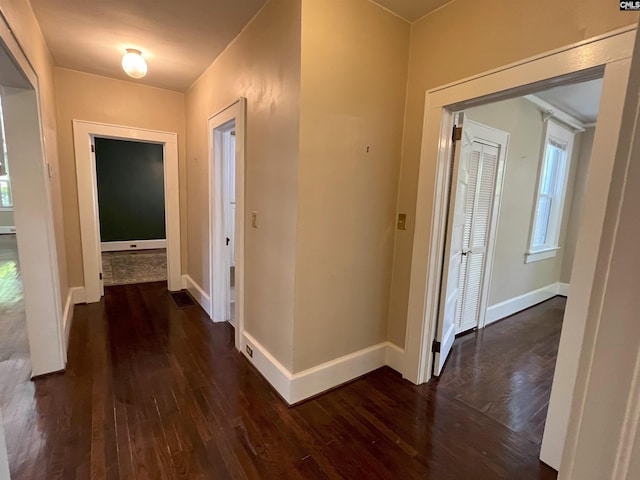 corridor featuring baseboards and dark wood-style flooring