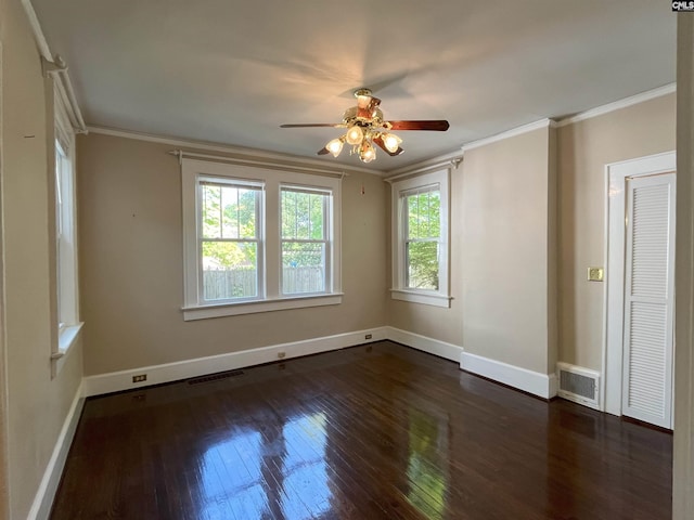 spare room featuring crown molding, dark wood-style flooring, a ceiling fan, baseboards, and visible vents
