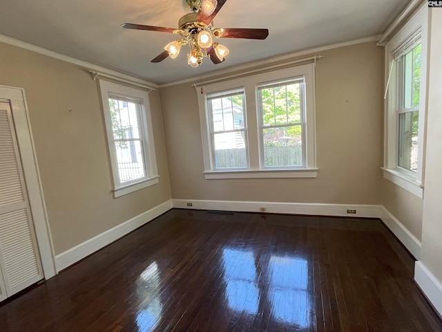 spare room with baseboards, ornamental molding, dark wood-style floors, and a healthy amount of sunlight