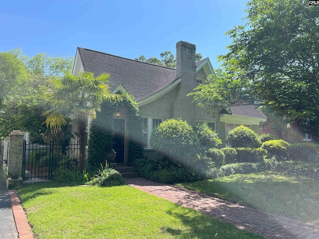 view of front of house with fence, a chimney, brick siding, and a front yard