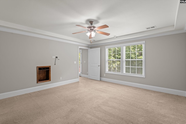 empty room with visible vents, baseboards, light colored carpet, a raised ceiling, and a ceiling fan