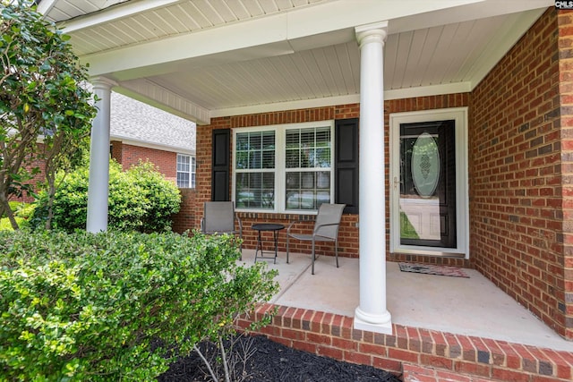 entrance to property with covered porch and brick siding