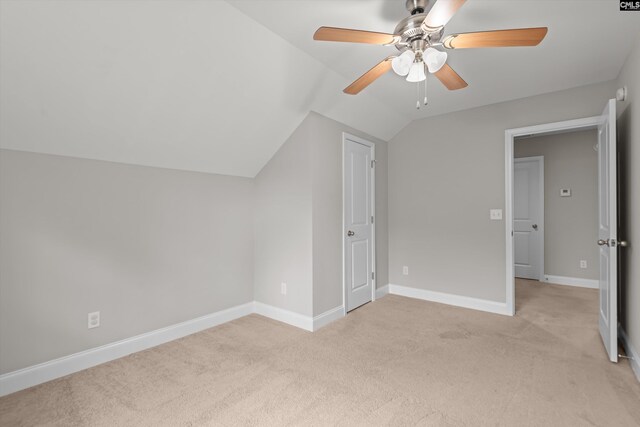 additional living space with light colored carpet, a ceiling fan, baseboards, and vaulted ceiling