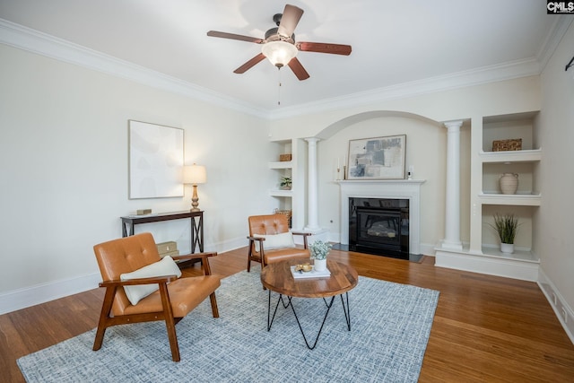 sitting room with crown molding, ceiling fan, decorative columns, and wood finished floors