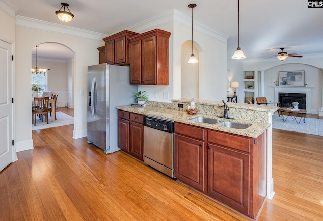 kitchen featuring a sink, arched walkways, stainless steel appliances, and light wood-style flooring