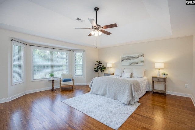 bedroom featuring baseboards, a ceiling fan, wood finished floors, and visible vents