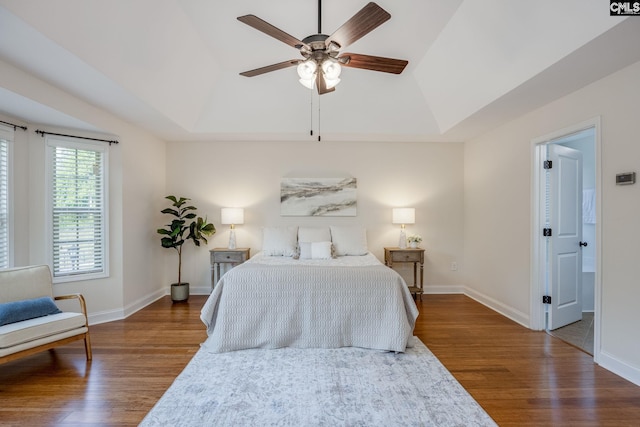bedroom featuring baseboards, wood finished floors, and lofted ceiling