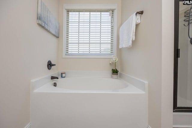 bathroom featuring a garden tub and a shower with shower door
