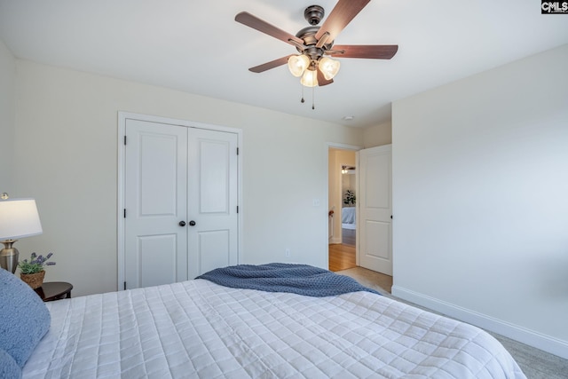 bedroom with light colored carpet, baseboards, ceiling fan, and a closet