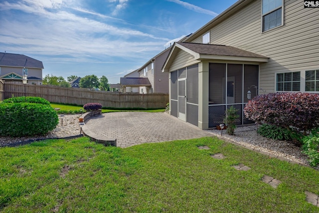view of yard with fence, a sunroom, and a patio area