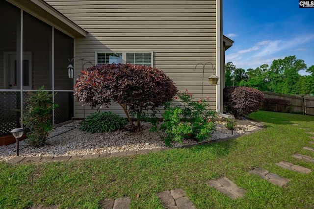 view of side of property featuring fence, a sunroom, and a yard