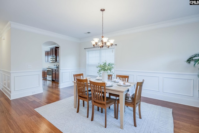 dining area featuring visible vents, arched walkways, dark wood-style floors, a notable chandelier, and ornamental molding