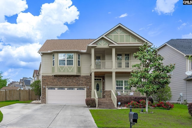 craftsman house with fence, a front yard, a balcony, covered porch, and driveway