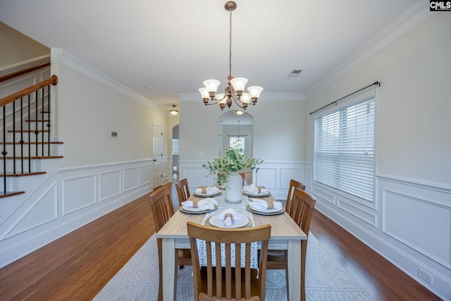 dining space with dark wood-type flooring, crown molding, a notable chandelier, and stairway