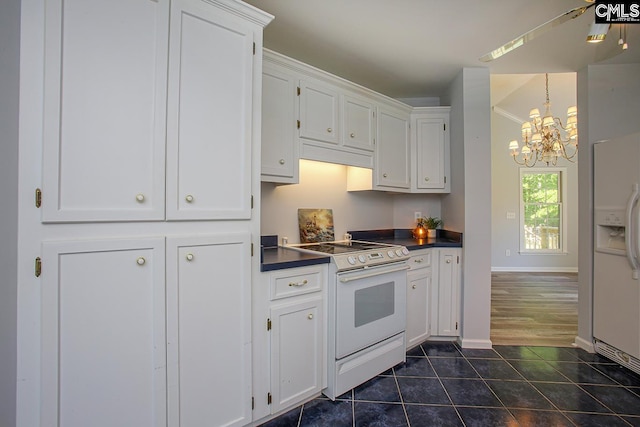 kitchen with dark tile patterned flooring, dark countertops, white cabinets, and white appliances