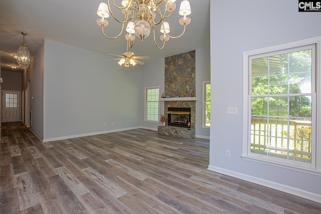 unfurnished living room with an inviting chandelier, plenty of natural light, a towering ceiling, and wood finished floors