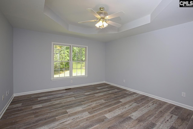 unfurnished room with baseboards, a ceiling fan, a tray ceiling, and wood finished floors