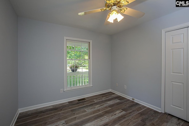 unfurnished room with baseboards, a ceiling fan, dark wood-style flooring, and visible vents