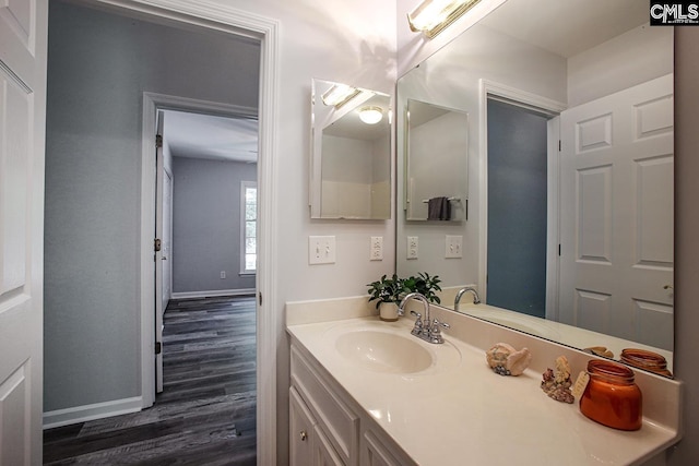 bathroom with baseboards, wood finished floors, and vanity