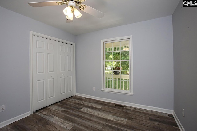 unfurnished bedroom featuring dark wood-style flooring, a ceiling fan, baseboards, visible vents, and a closet