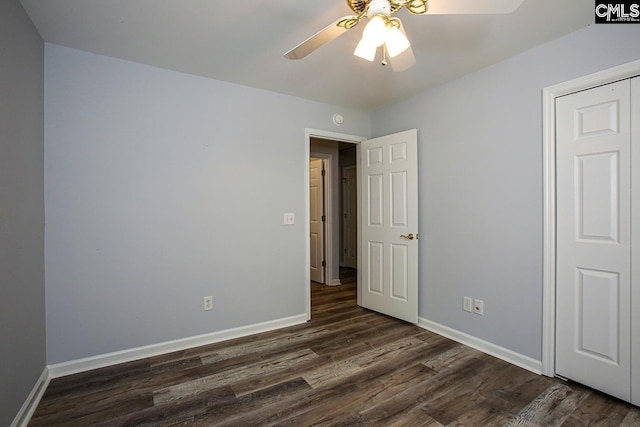 unfurnished bedroom featuring dark wood-type flooring, a ceiling fan, and baseboards
