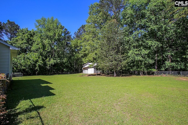 view of yard with a storage shed, fence, and an outbuilding