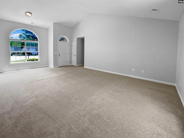 carpeted empty room with baseboards, visible vents, and high vaulted ceiling