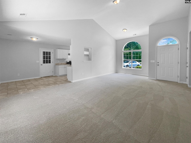 unfurnished living room featuring light colored carpet, baseboards, visible vents, and high vaulted ceiling
