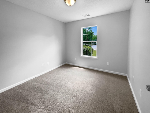 carpeted empty room featuring visible vents, a textured ceiling, and baseboards