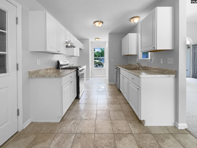 kitchen with under cabinet range hood, stainless steel appliances, white cabinetry, and light countertops