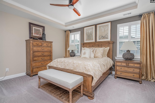 bedroom featuring ornamental molding, a tray ceiling, light colored carpet, and visible vents