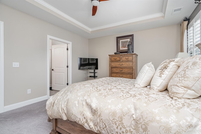 carpeted bedroom featuring a raised ceiling, a ceiling fan, baseboards, visible vents, and ornamental molding