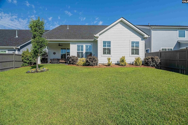 rear view of property with a lawn, ceiling fan, and a fenced backyard