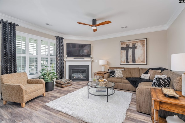 living room featuring crown molding, a ceiling fan, wood finished floors, and visible vents