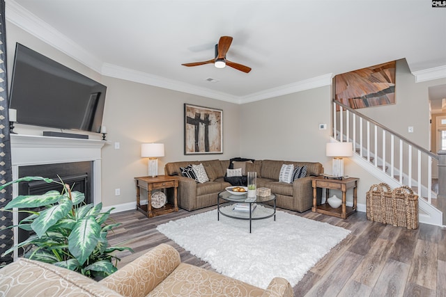 living area with crown molding, baseboards, stairs, and wood finished floors