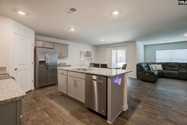 kitchen featuring visible vents, appliances with stainless steel finishes, a sink, gray cabinetry, and dark wood-style floors