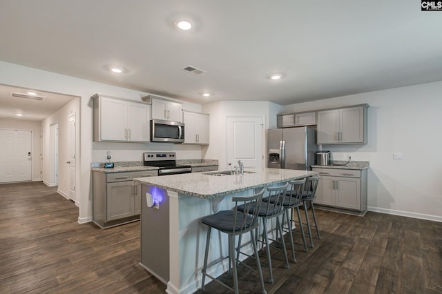 kitchen with gray cabinets, appliances with stainless steel finishes, a sink, and dark wood finished floors