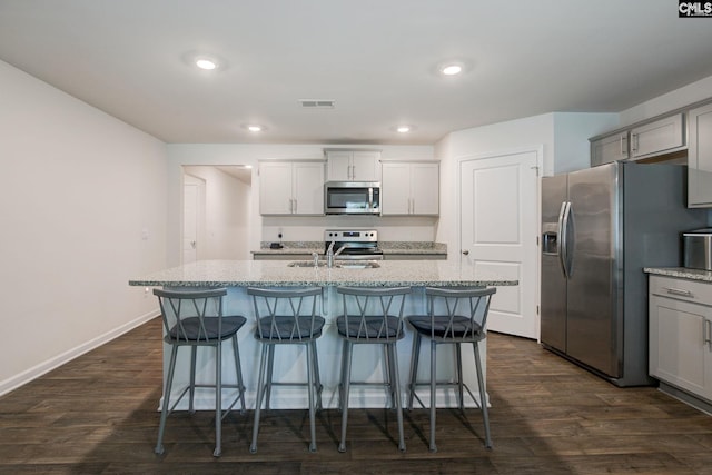 kitchen featuring visible vents, dark wood-style flooring, appliances with stainless steel finishes, and a kitchen bar
